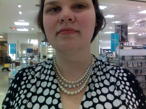 A picture of me wearing a tripple-row of pearls, each strand longer than the next. The middle row has sparkly faux-diamonds in the centre.  